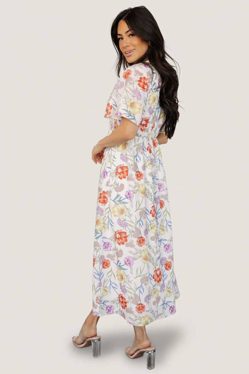 Detail view of smocked front bodice and elastic waistband on an ivory floral rayon midi dress, highlighting texture and fit shaping.