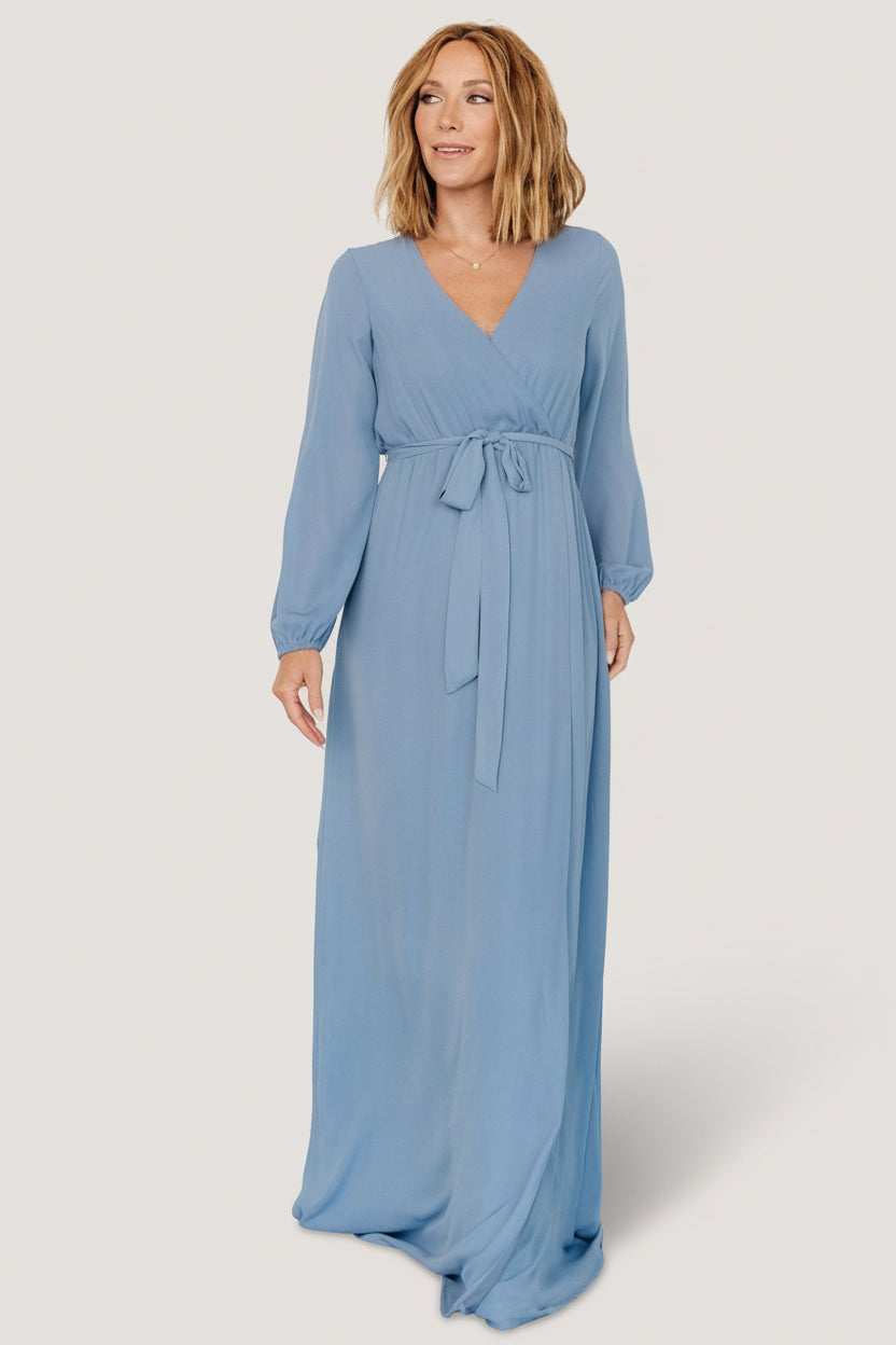 Styled shot of Breanne Faux Wrap Maxi Dress in slate blue worn for a wedding-guest look, showing length, neckline and overall occasion-ready styling.