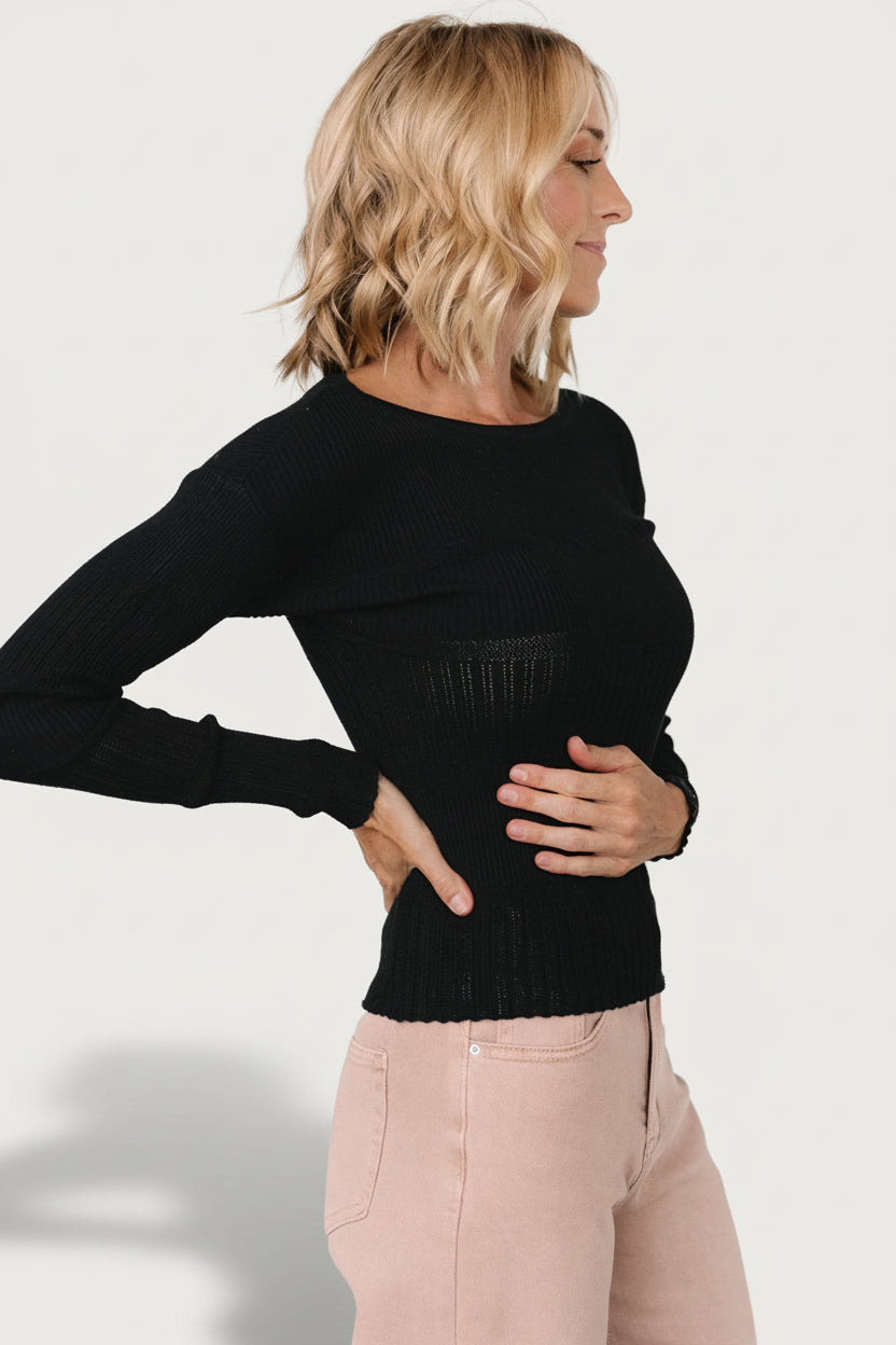 Side profile of the black Bren sweater top on model, showing fitted sleeve length and streamlined silhouette.