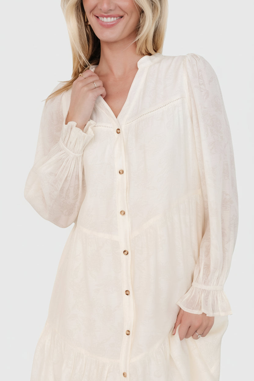 Close-up of opaque floral rayon fabric and functional front buttons on the cream Brenna midi dress, showing print and texture.