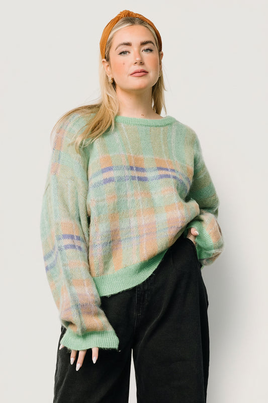 Front view of women's green multi plaid chunky knit sweater with round neckline, drop-shoulder sleeves, ribbed cuffs, and hem, on a model.