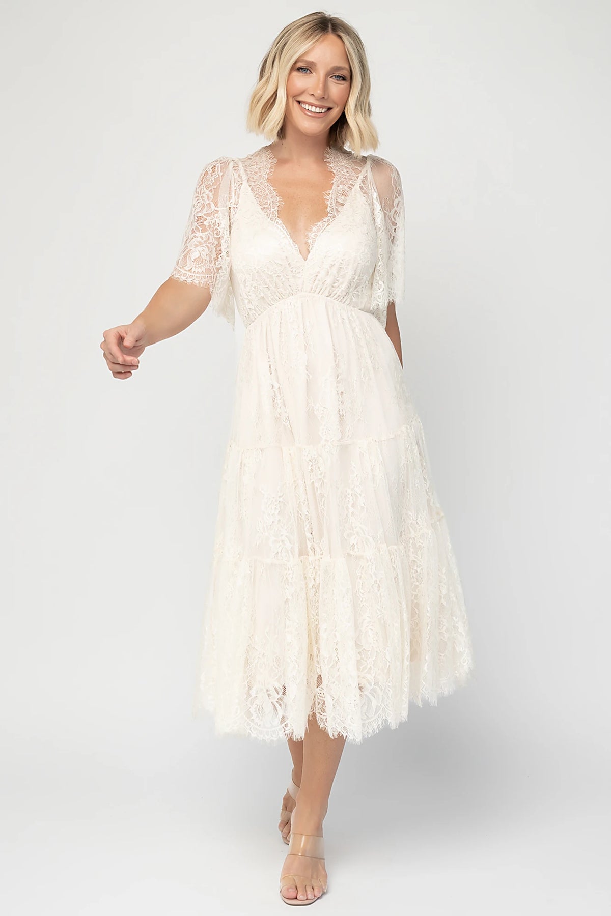Brittany Lace Midi Dress in Vintage Cream with deep V-neck, sheer lace sleeves, elastic waist, and tiered skirt.