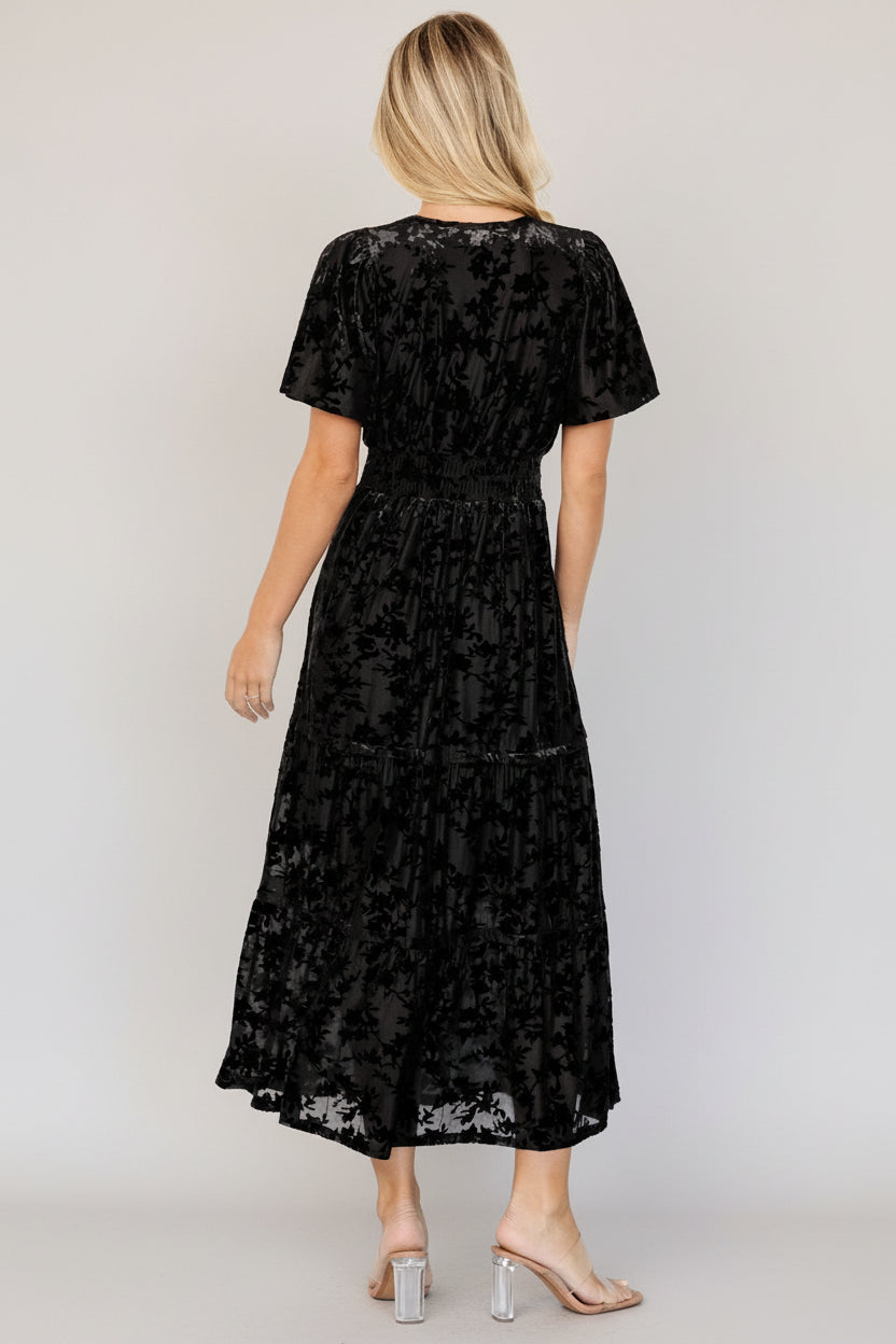 Back view of the Bronwyn burnout velvet dress in black showing gathered bodice, smocked waist and tiered skirt silhouette.