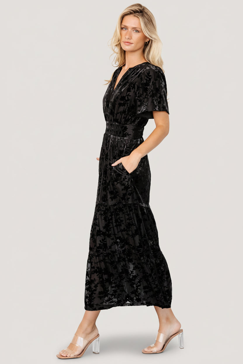 Model wearing the Bronwyn velvet midi dress in black, showing fit at the waist, sleeve length and lined skirt to mid-thigh.