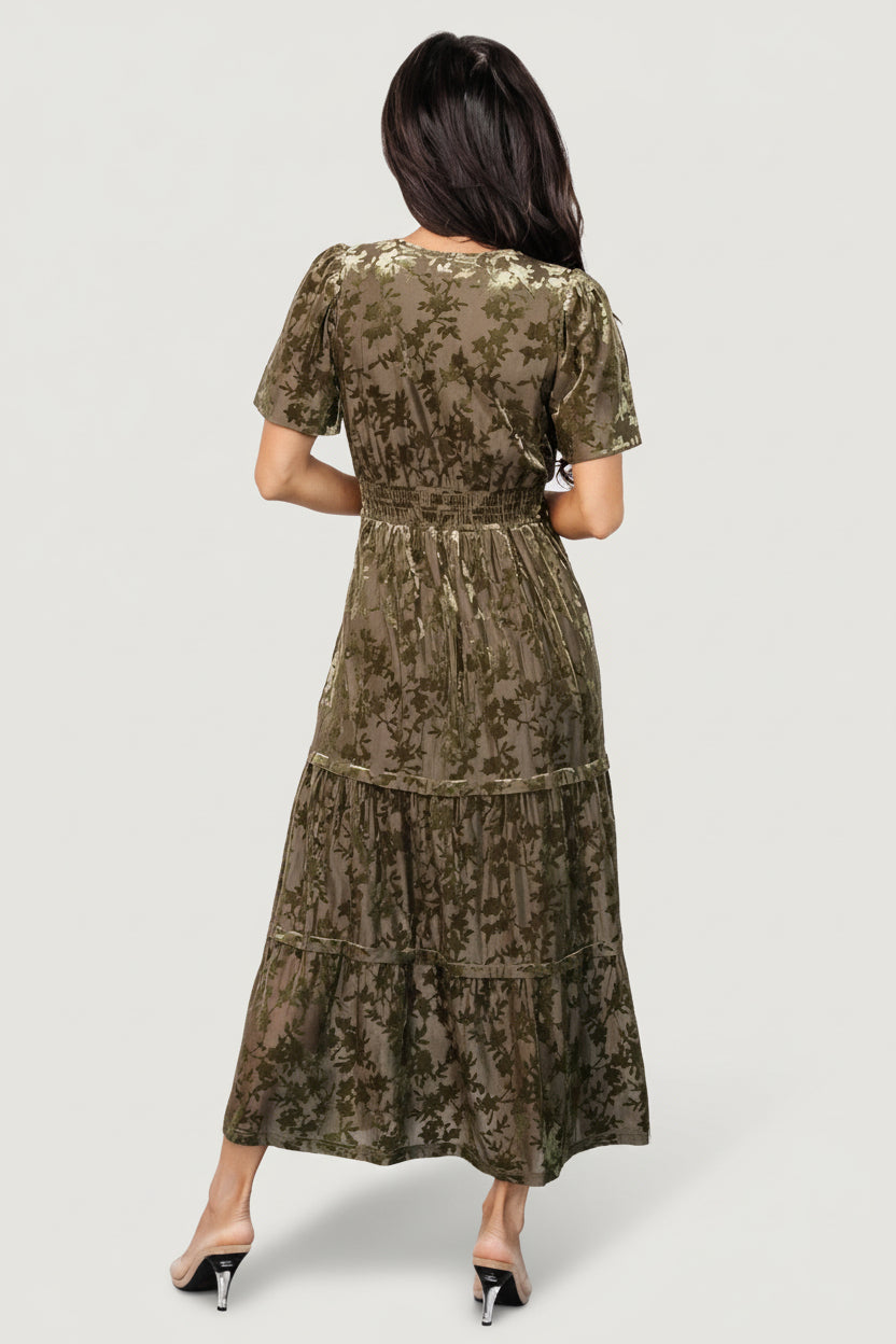 Lifestyle image of a model wearing the olive velvet midi dress, highlighting flutter sleeves, hidden side pockets and natural movement.