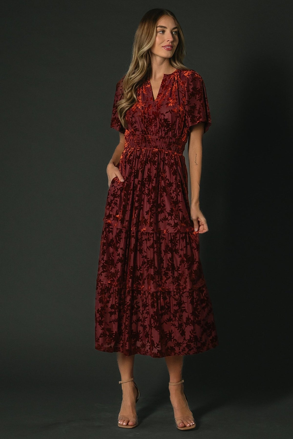 Close-up detail of Bronwyn burnout velvet fabric in rust floral on burgundy background highlighting velvet texture and floral patterning.