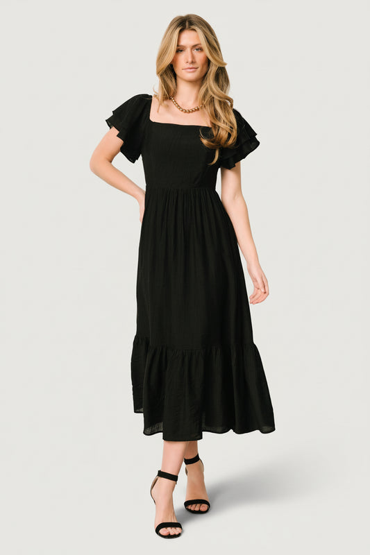 Front view of a black midi dress with square neckline, smocked back, tiered ruffle sleeves, and ruffle-tier skirt for feminine movement.