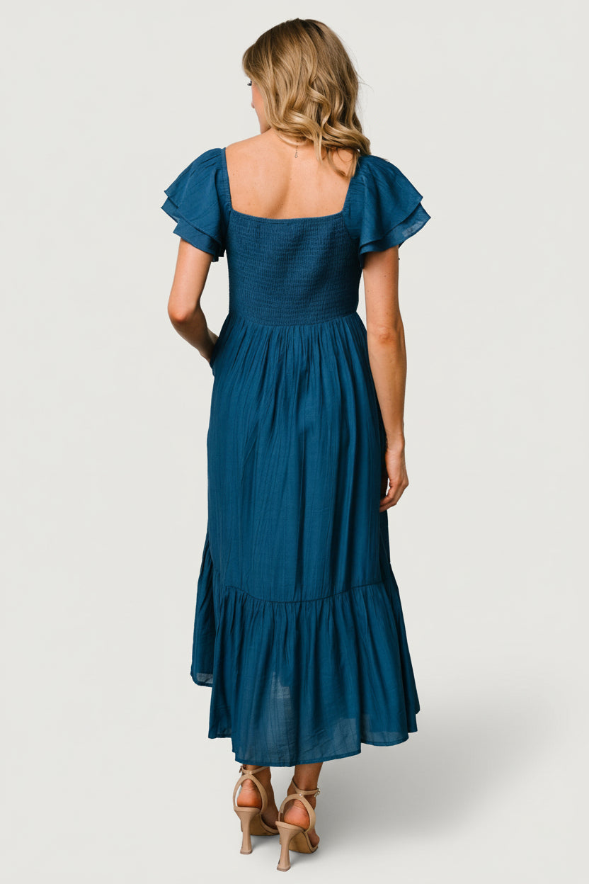 Detail of tiered midi skirt and ruffle tier showing movement, midi length, and layered silhouette in deep blue fabric.
