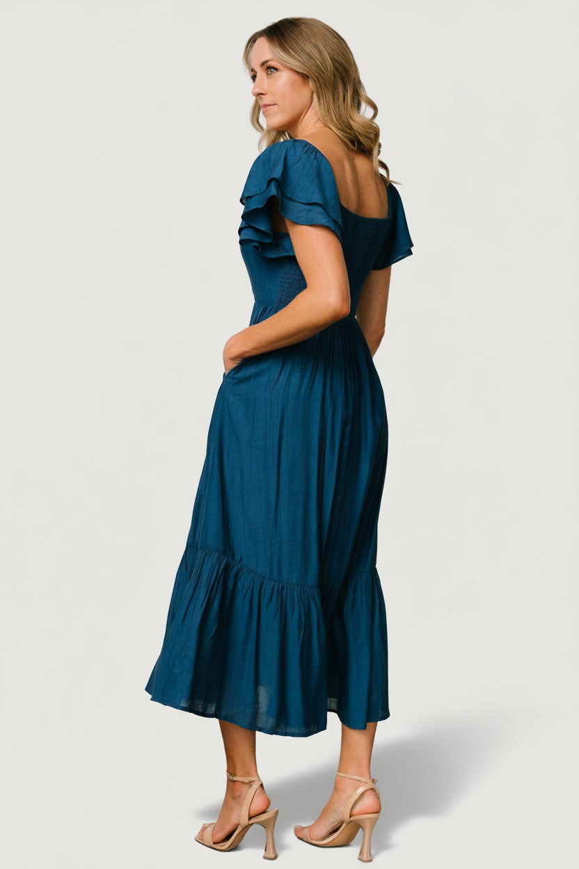 Close-up of ruffle sleeve and shoulder elastic, illustrating feminine movement and detailed construction in deep blue fabric.