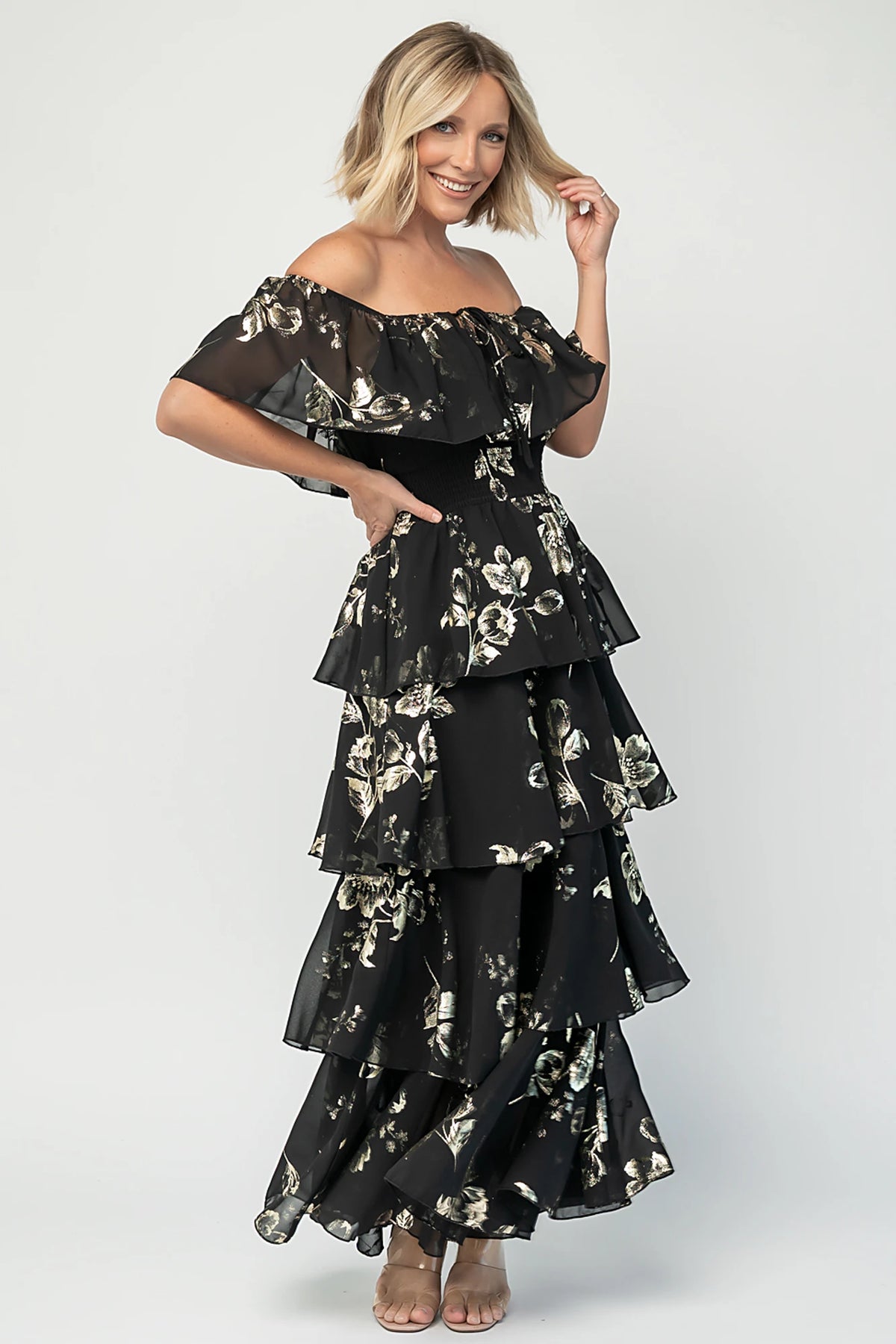 Carina Off Shoulder Maxi Dress in Black + Gold with floral print, ruffle neckline, smocked waist, and tiered chiffon skirt.