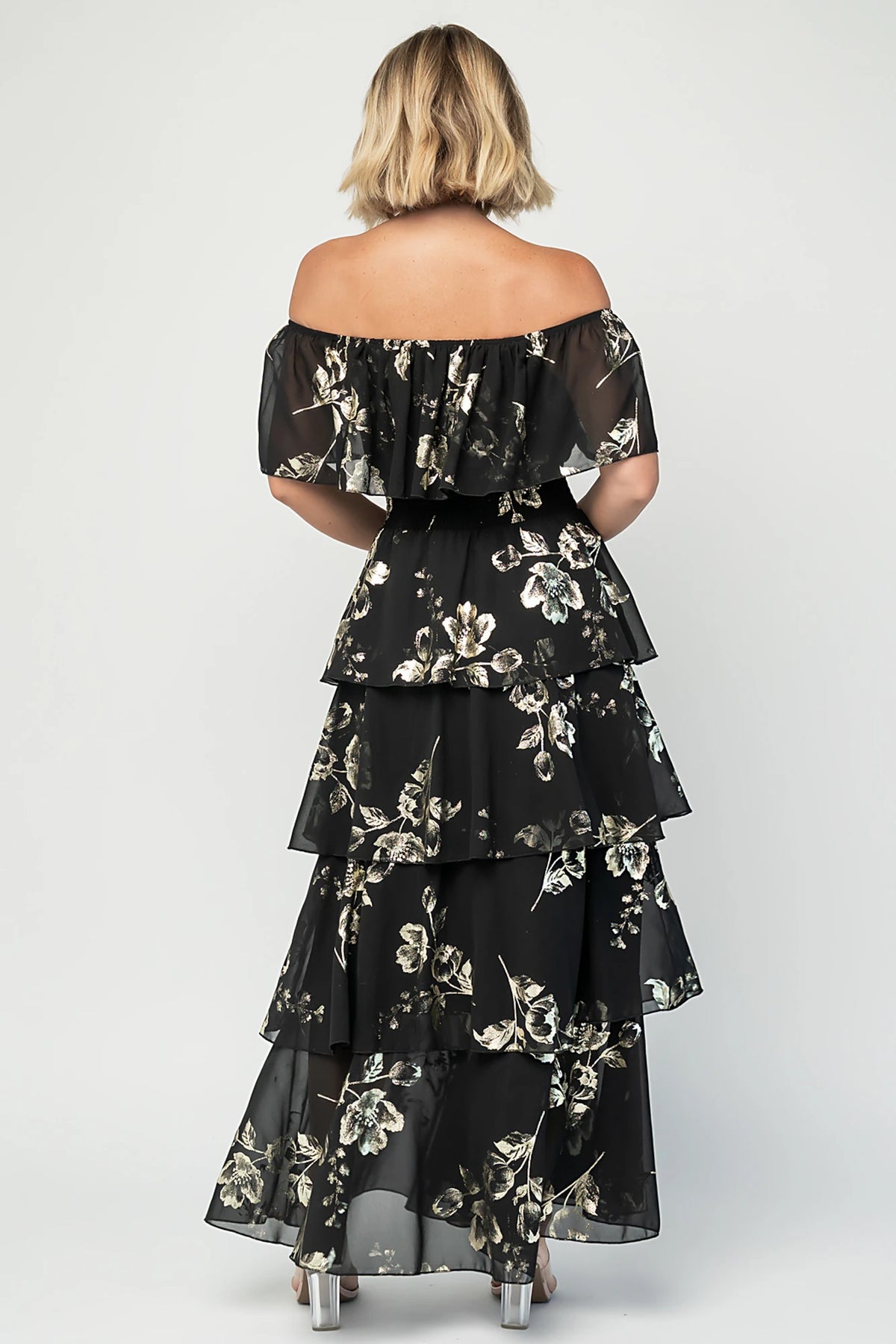 Carina Off Shoulder Maxi Dress in Black + Gold with floral print, ruffle neckline, smocked waist, and tiered chiffon skirt.