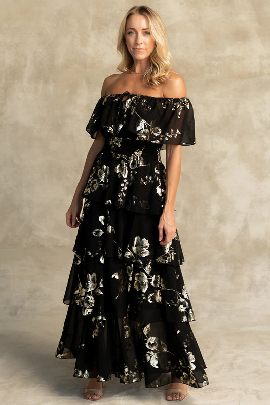 Carina Off Shoulder Maxi Dress in Black + Gold with floral print, ruffle neckline, smocked waist, and tiered chiffon skirt.