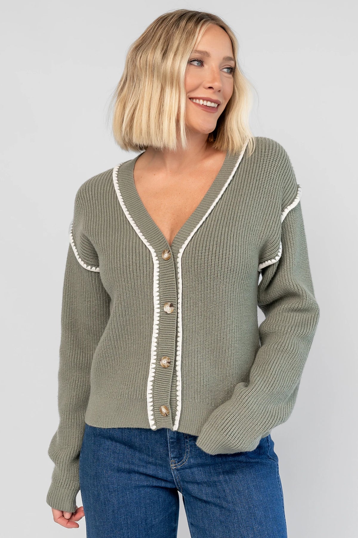Clarke Button Up Cardigan in Dusty Sage with tortoise-colored buttons, white piping details, and a button-front design.