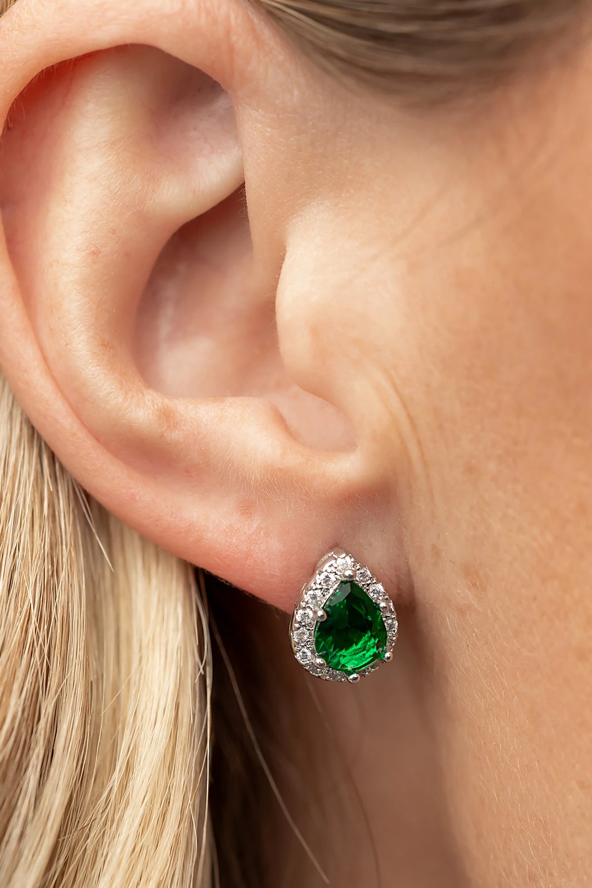 Dacia Pear Cut Stud Earrings in Emerald with pear-cut green stones, clear stone halos, and silver-tone settings.