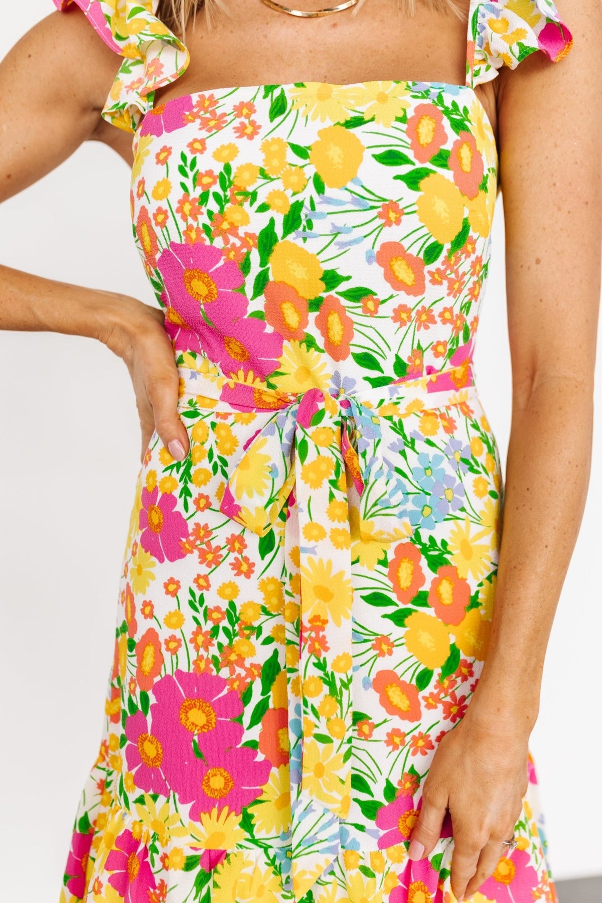 Three-quarter view of floral chiffon midi dress highlighting tiered skirt, removable waist tie, and flowing ruffle detail.
