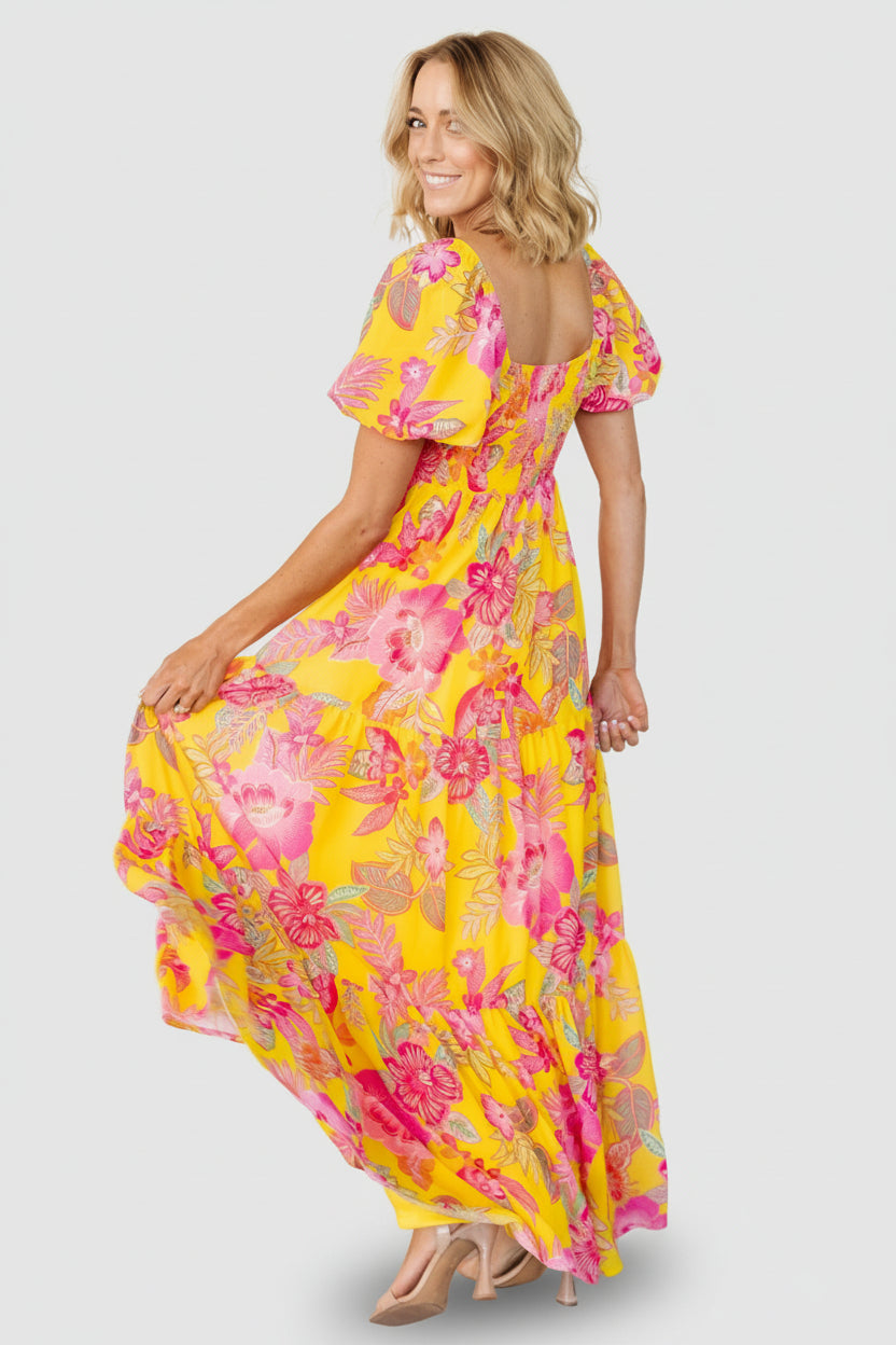 Model wearing yellow and pink floral Darla dress, showing length, puffed sleeves and how the empire waist sits under the bust.
