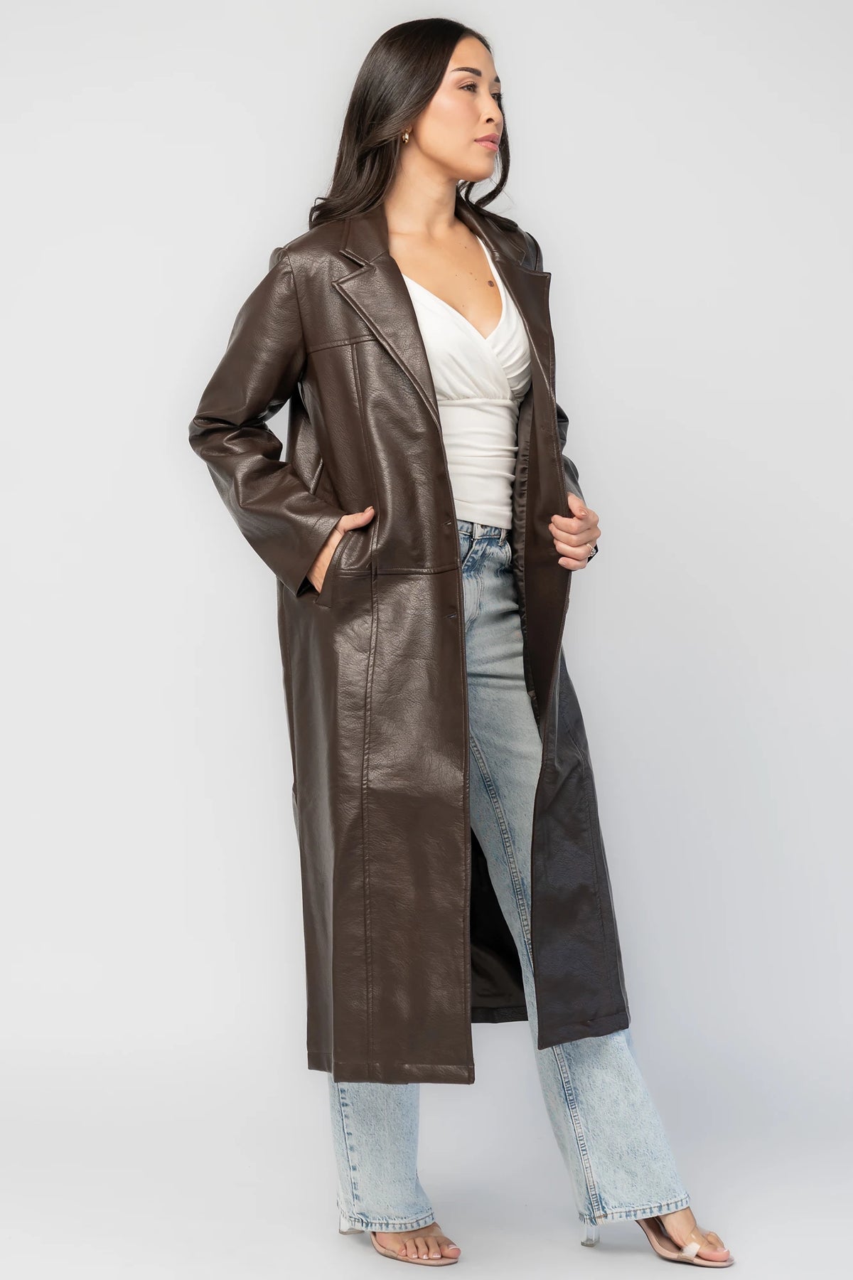 Dove Coat in Brown Faux Leather with notched collar, button front, long sleeves, patch pockets, and longline silhouette.