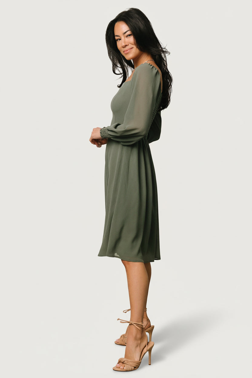 Studio image of dark sage short dress laid lengthwise to show hemline, lining, and sleeve cuff details