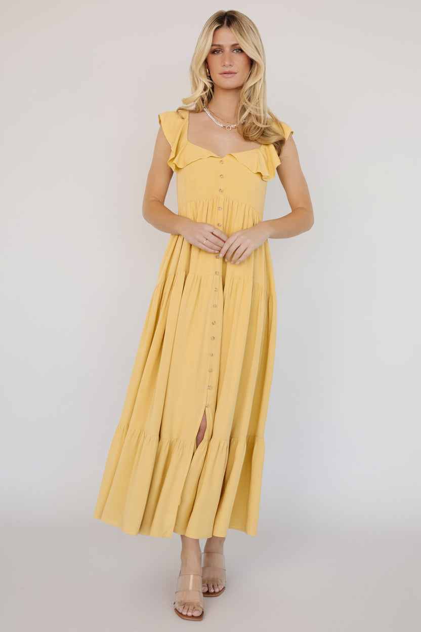 Close-up of ruffle V-neckline and faux button front on the golden yellow dress showing fabric texture and layered ruffle overlay.