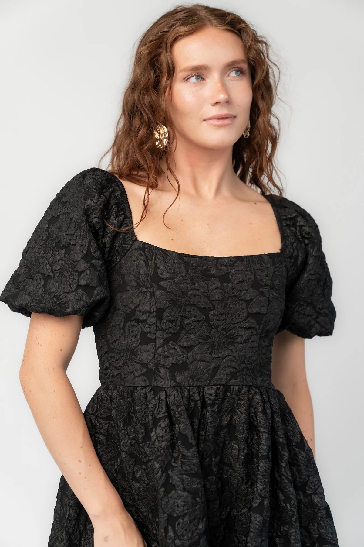 Enchanted Jacquard Dress in Black with textured florals, square neckline, puff sleeves, pleated waist, and A-line skirt.