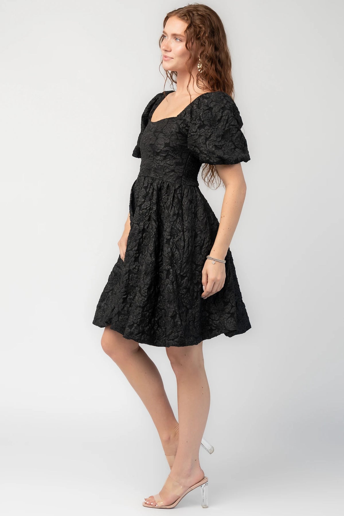 Enchanted Jacquard Dress in Black with textured florals, square neckline, puff sleeves, pleated waist, and A-line skirt.