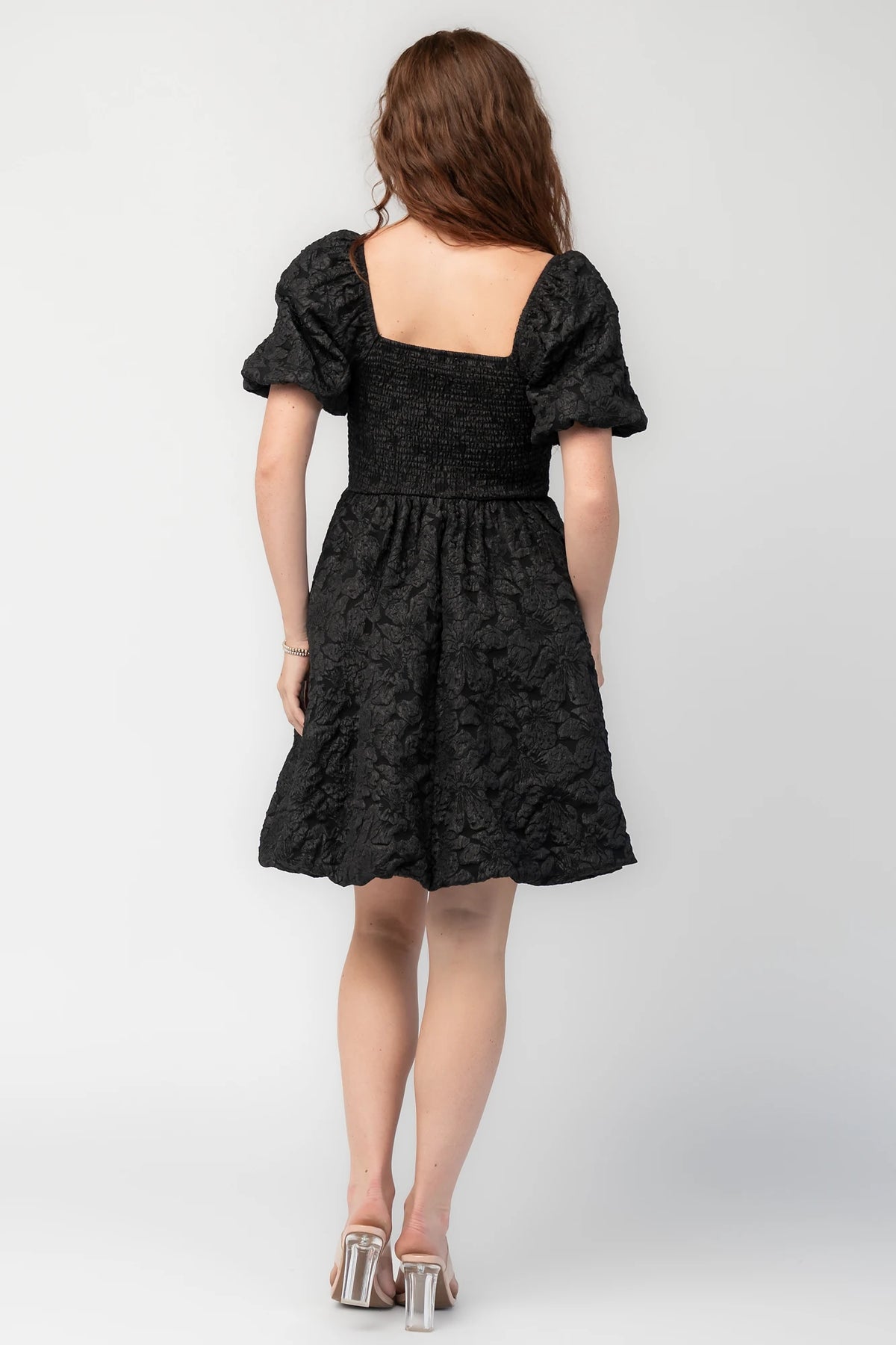 Enchanted Jacquard Dress in Black with textured florals, square neckline, puff sleeves, pleated waist, and A-line skirt.