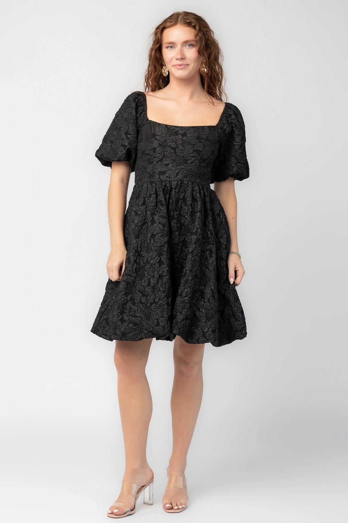 Enchanted Jacquard Dress in Black with textured florals, square neckline, puff sleeves, pleated waist, and A-line skirt.