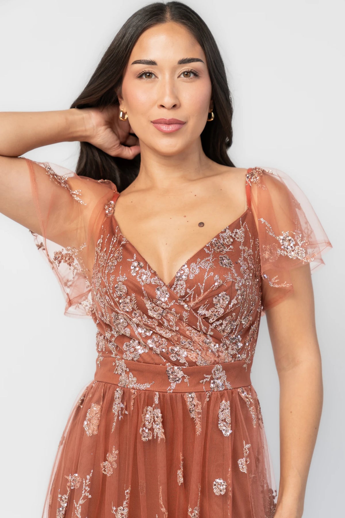 Esmerelda Shimmer Gown in Terracotta with floral sequin embroidery, surplice V-neckline, flutter sleeves, and front slit.