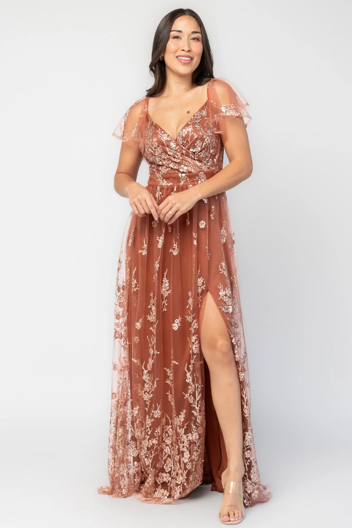 Esmerelda Shimmer Gown in Terracotta with floral sequin embroidery, surplice V-neckline, flutter sleeves, and front slit.