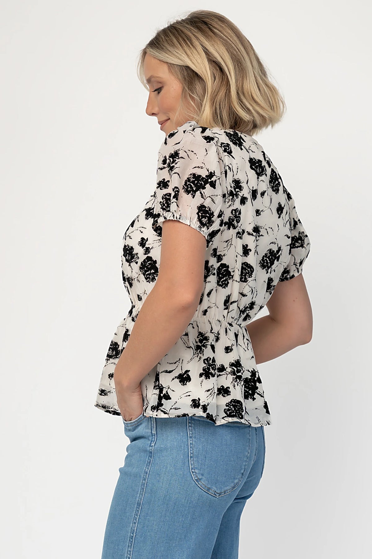 Gwenyth Peplum Blouse in Ivory + Black with velvet florals, front bow, puff sleeves, and elastic peplum waist.