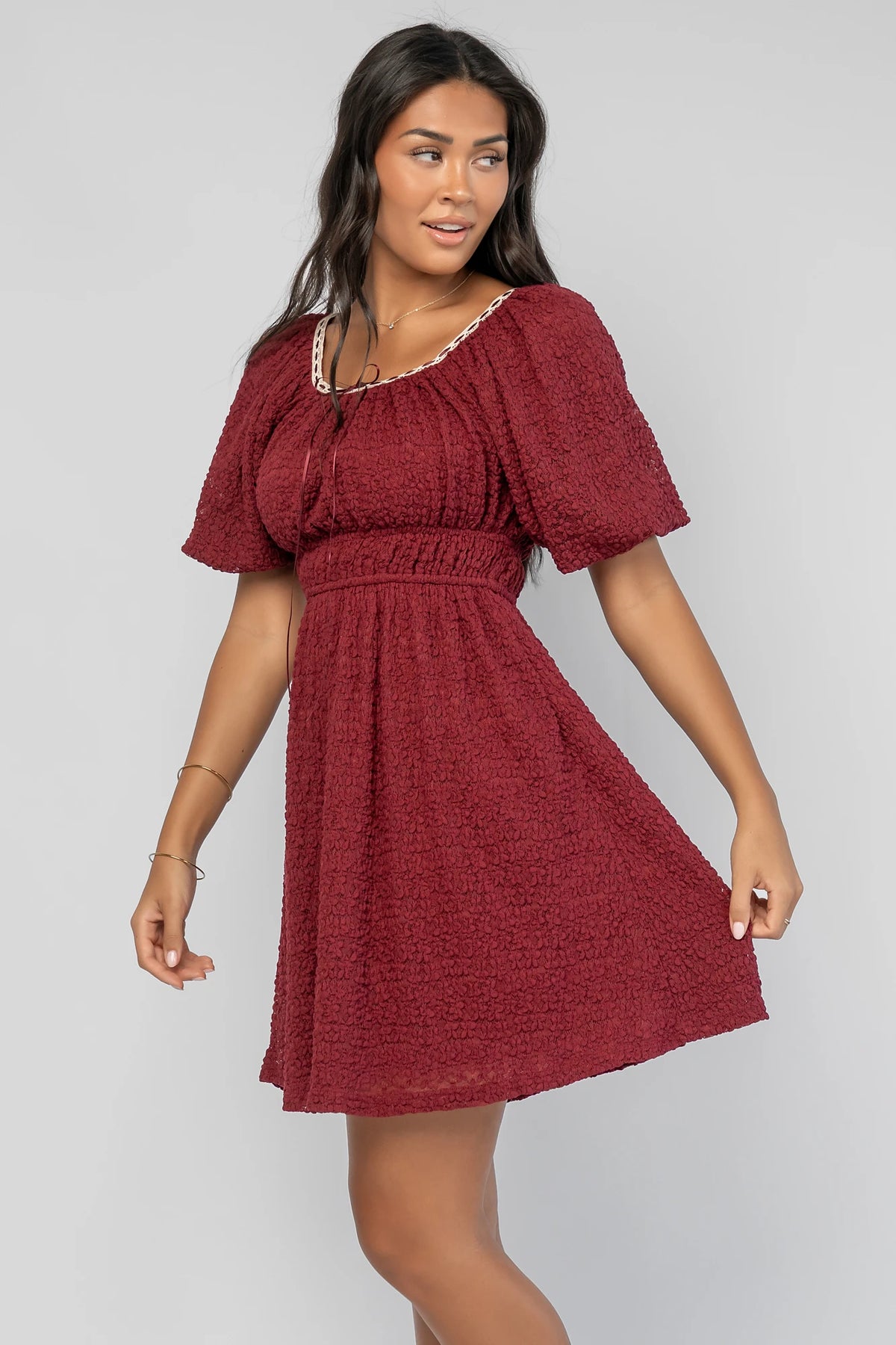 Gwyneth Short Dress in Burgundy with textured floral lace, scoop neckline, cream lace piping, and elastic sleeve cuffs.