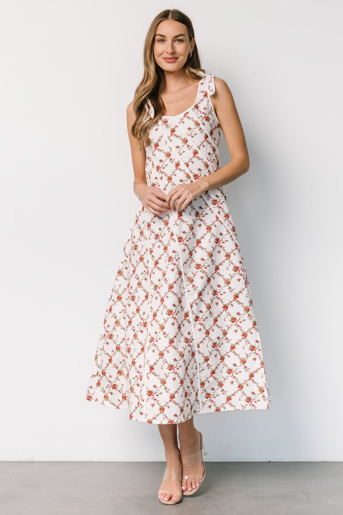 Lifestyle image of a model wearing the off-white red floral midi dress paired with sandals; showcases fit, length, and natural movement.