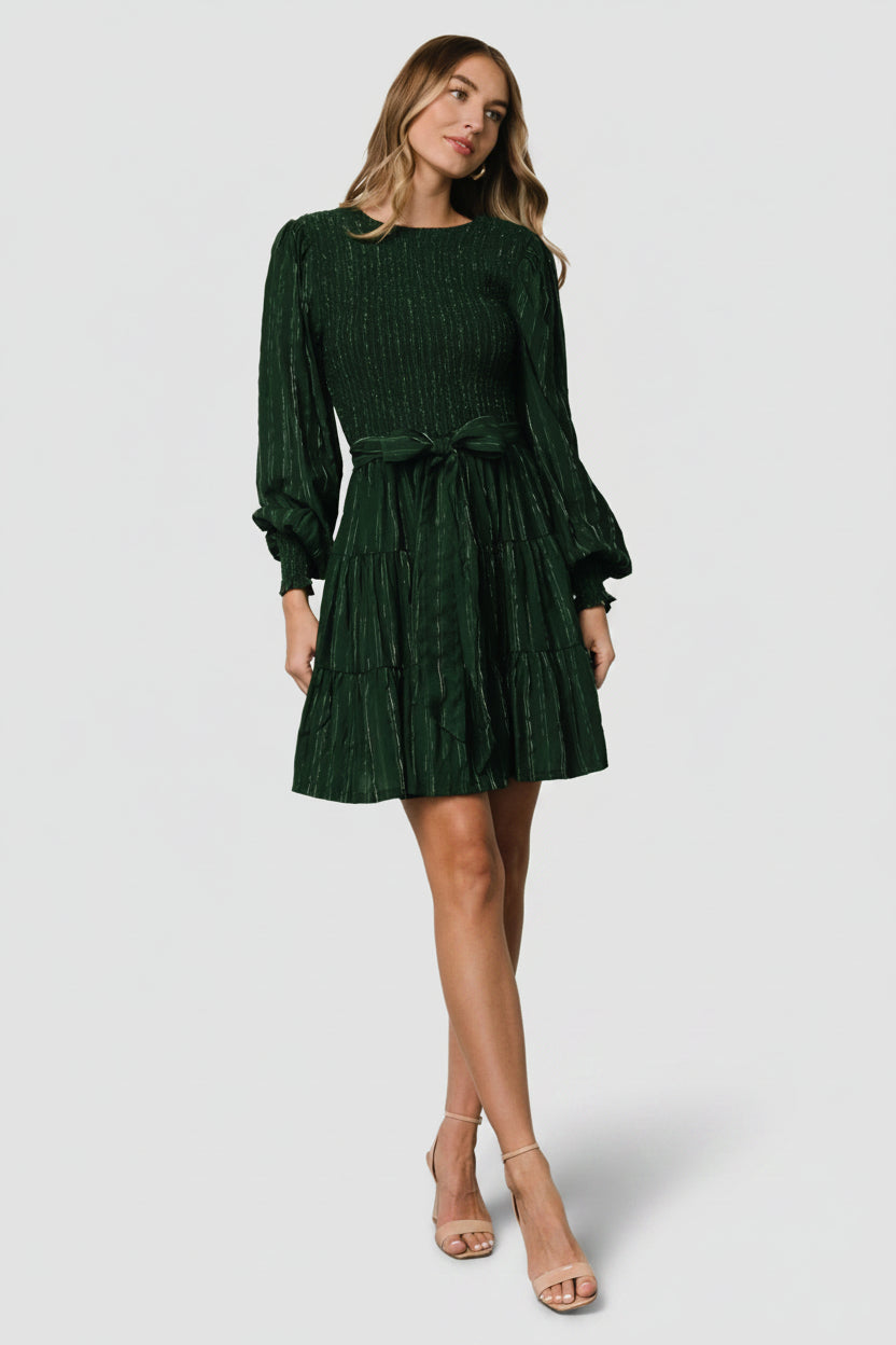 Detail shot of fabric texture showing dark green ground with subtle silver pinstripes and the lightweight tiered skirt construction.