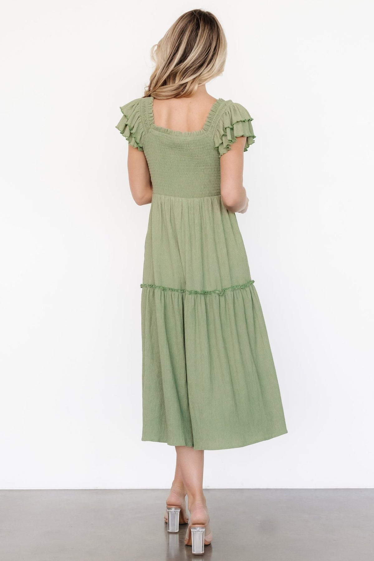 Back view of the Jacie Smocked Midi Dress in sage green, showing smocked back bodice, relaxed fit, and midi hemline in natural light.