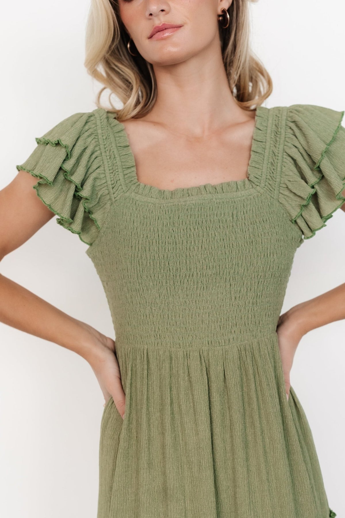 Three-quarter angle showing the Jacie Smocked Midi Dress in sage, highlighting smocked back, one-tier midi skirt, and concealed side pocket detail on model.