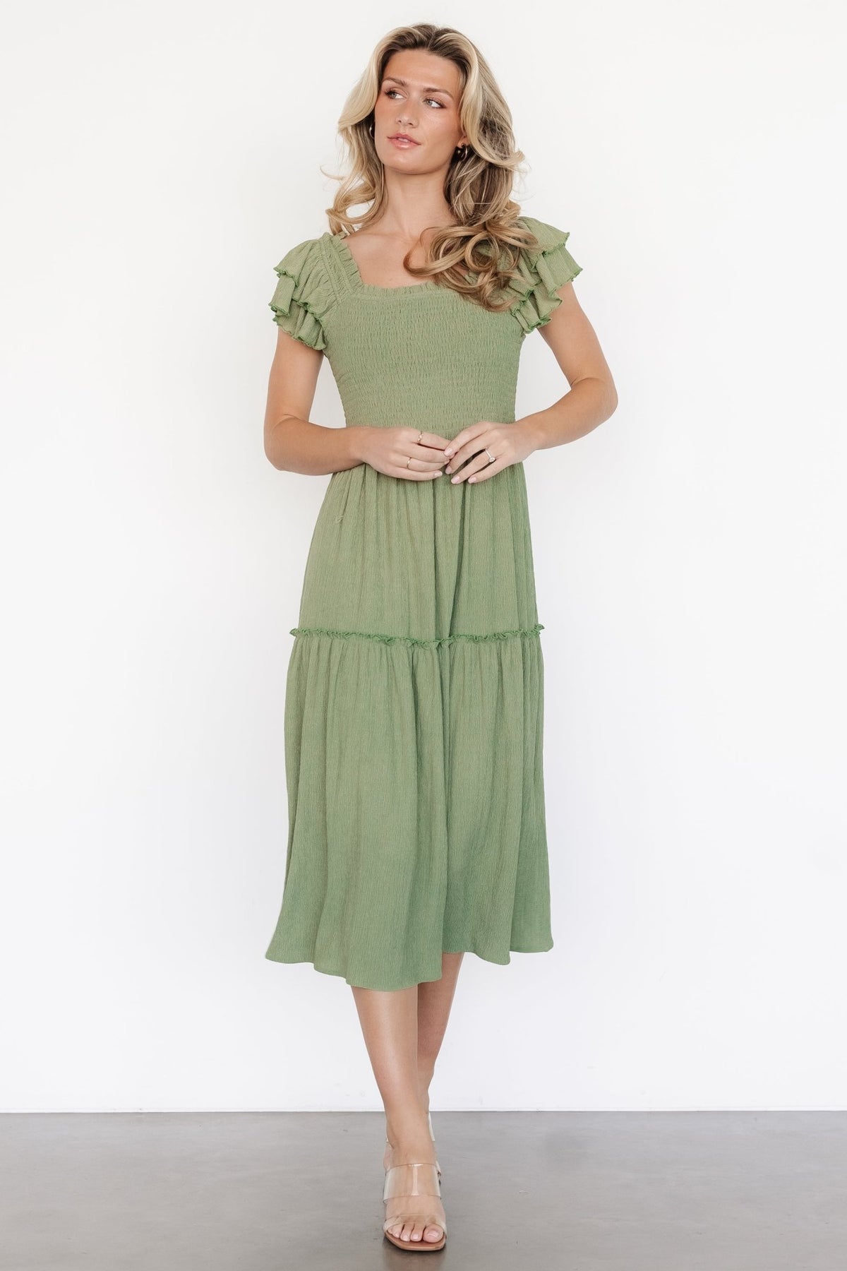 Close-up of the Jacie Smocked Midi Dress fabric and square neckline in sage, showing textured polyester-spandex material and ruffle sleeve detail.
