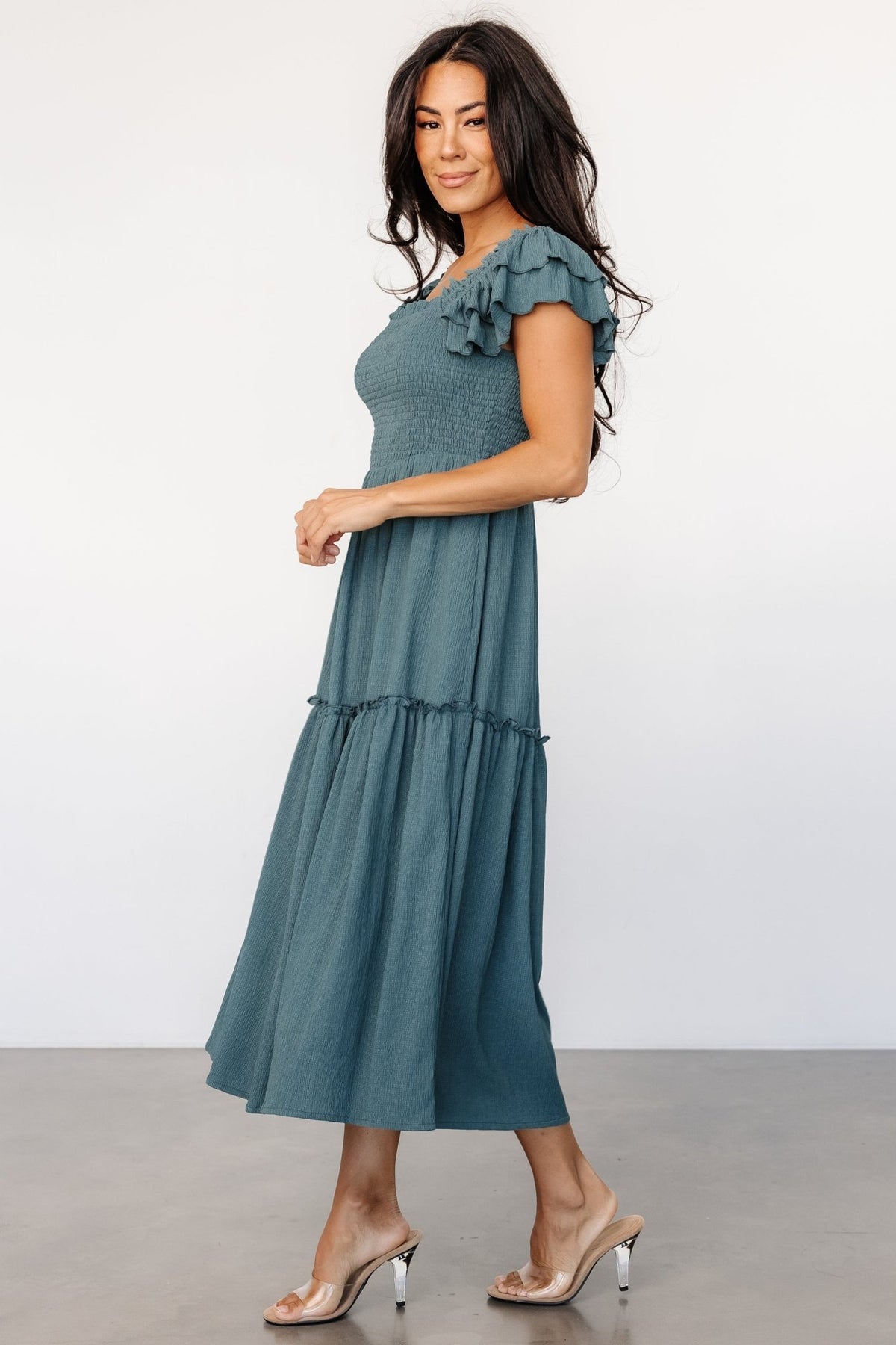 Model styling of the Jacie Smocked Midi Dress in vintage teal with ankle boots, showing hidden pocket access and relaxed, versatile midi silhouette.