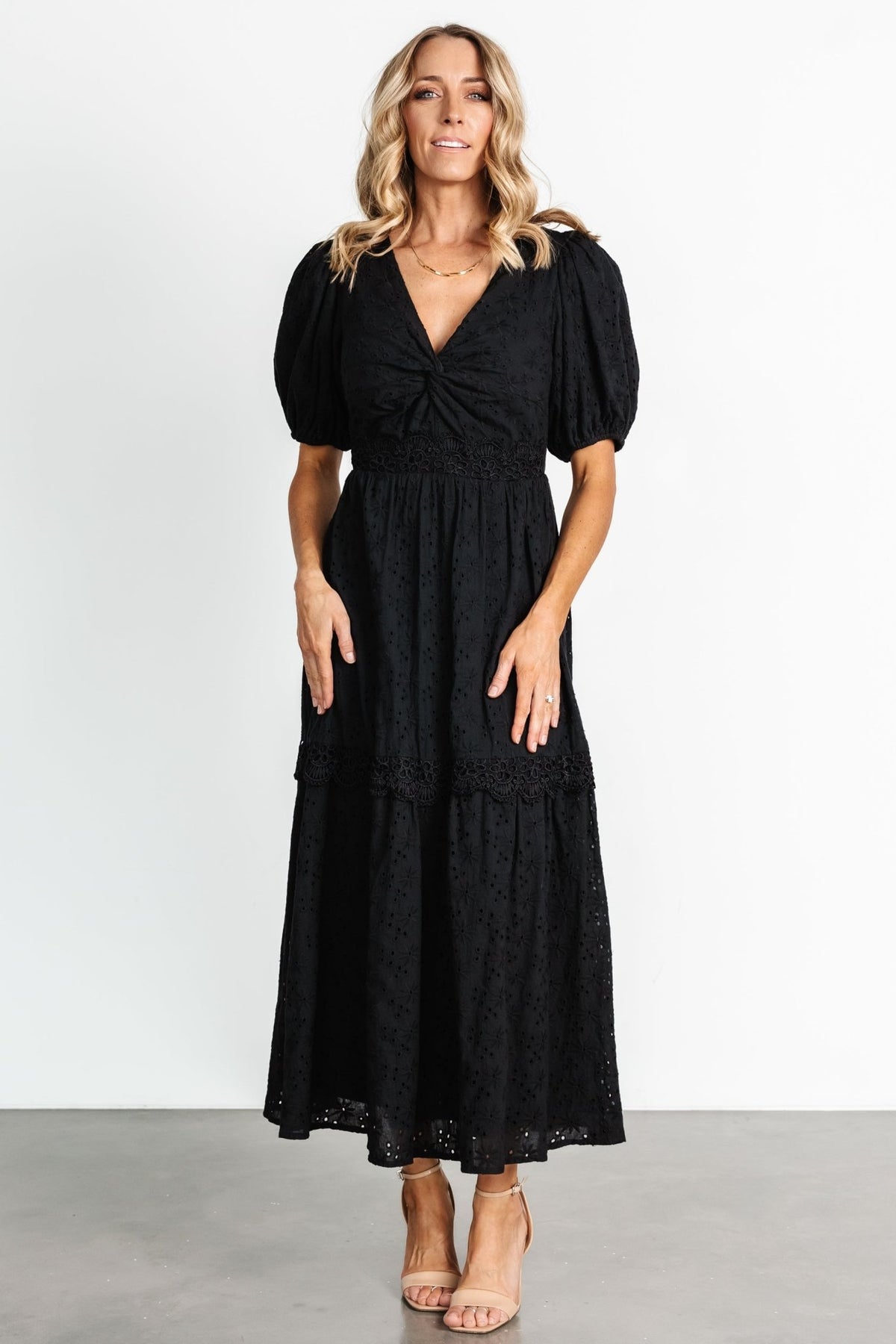Three-quarter view of dress on model highlighting mid-length puff sleeves, elastic cuffs and the flattering V-neck silhouette with eyelet details.