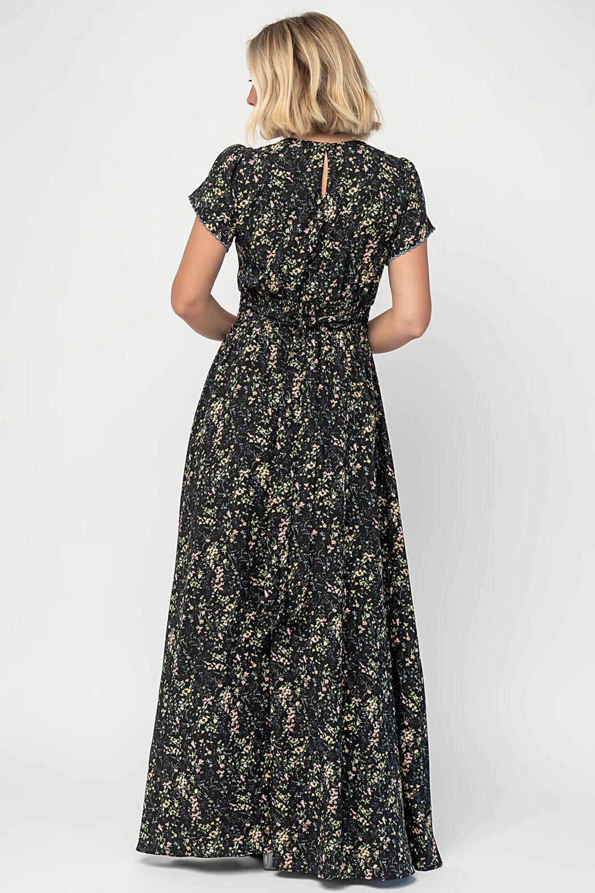 Jada Maxi Dress in Black Floral with V-neckline, blue scalloped trim, flutter sleeves, empire waist, and tie waist.