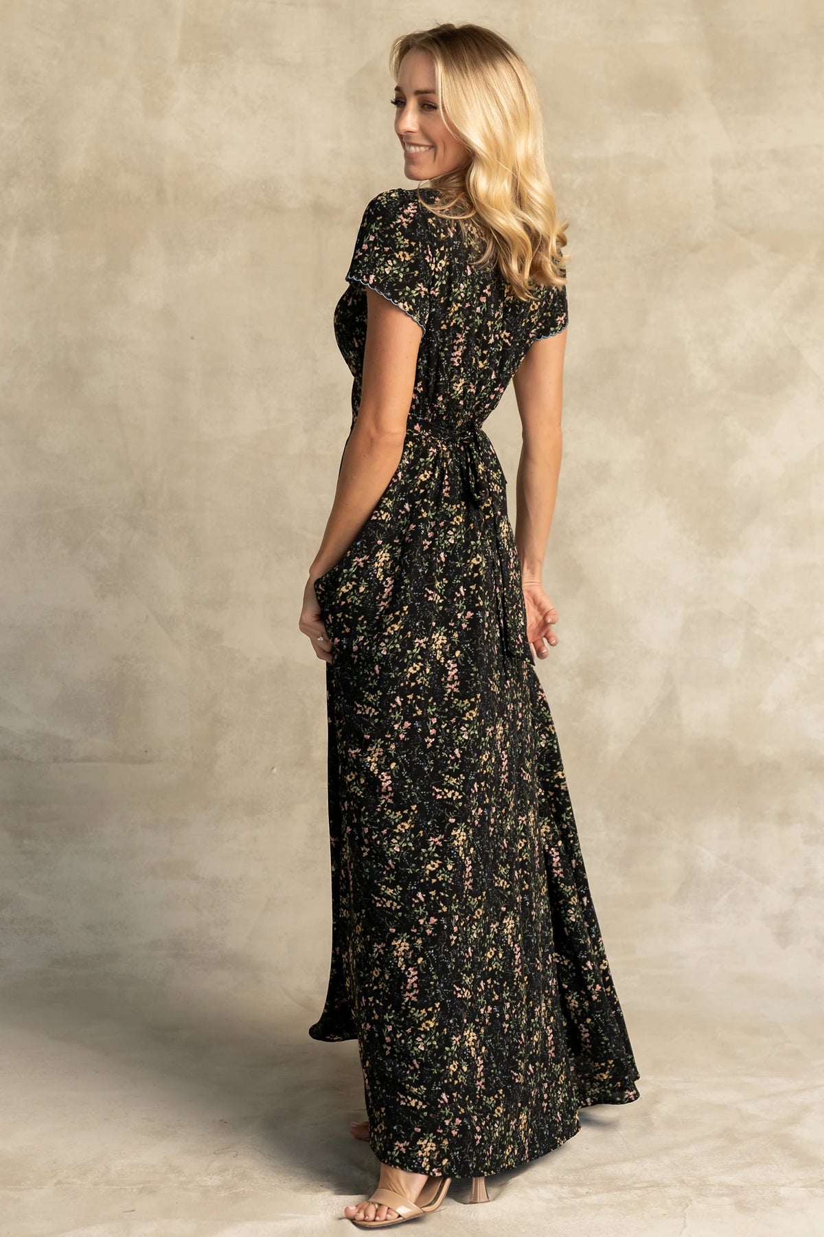 Jada Maxi Dress in Black Floral with V-neckline, blue scalloped trim, flutter sleeves, empire waist, and tie waist.