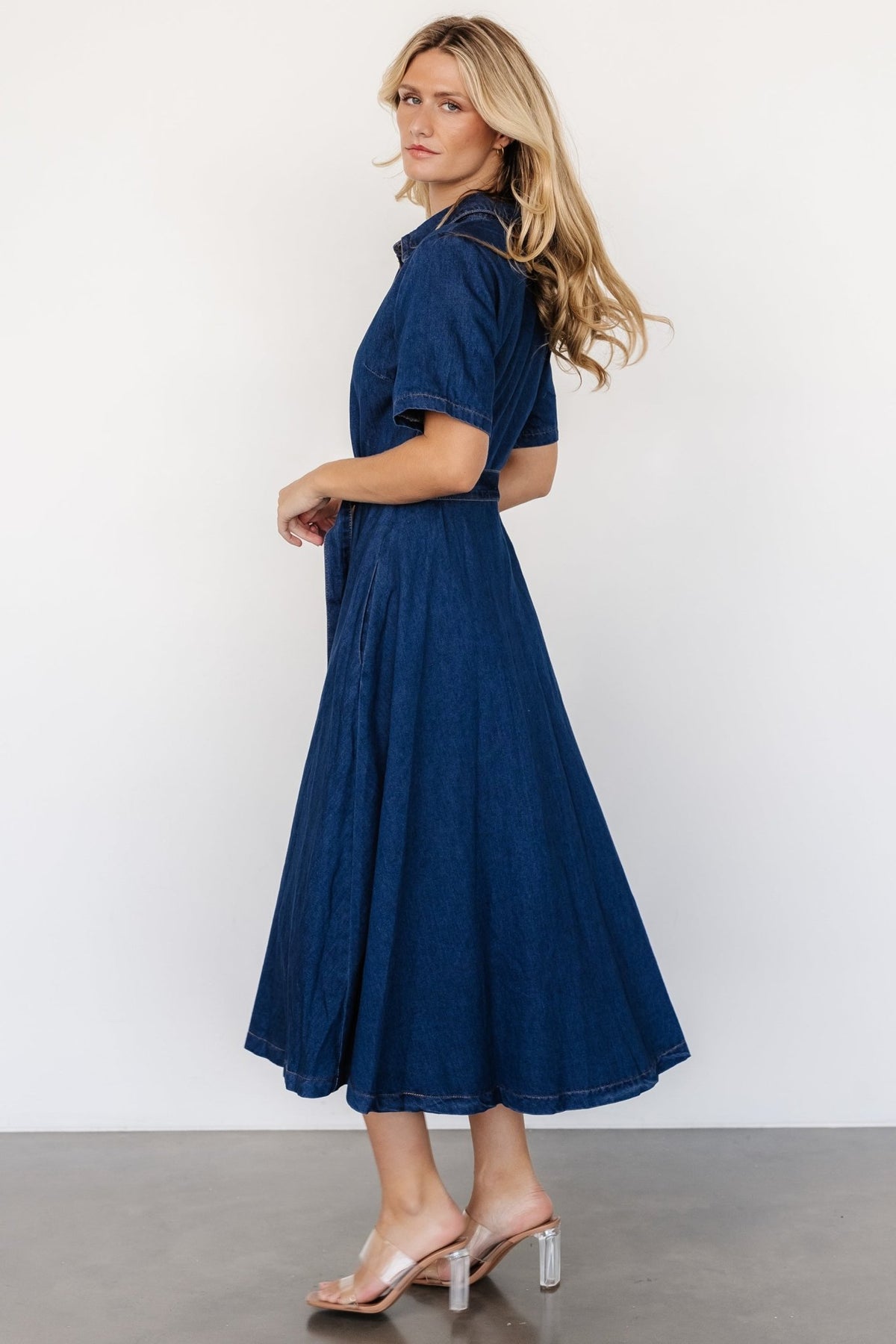 Side view highlighting functional side pocket, waistline silhouette, and adjustable self-fabric belt in denim.