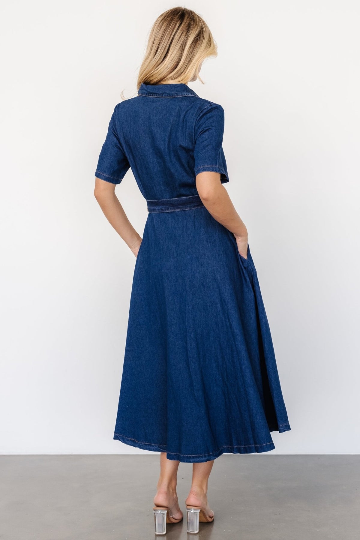 Back view of midi dress showing seam lines, hem length, and overall structured denim silhouette on mannequin.