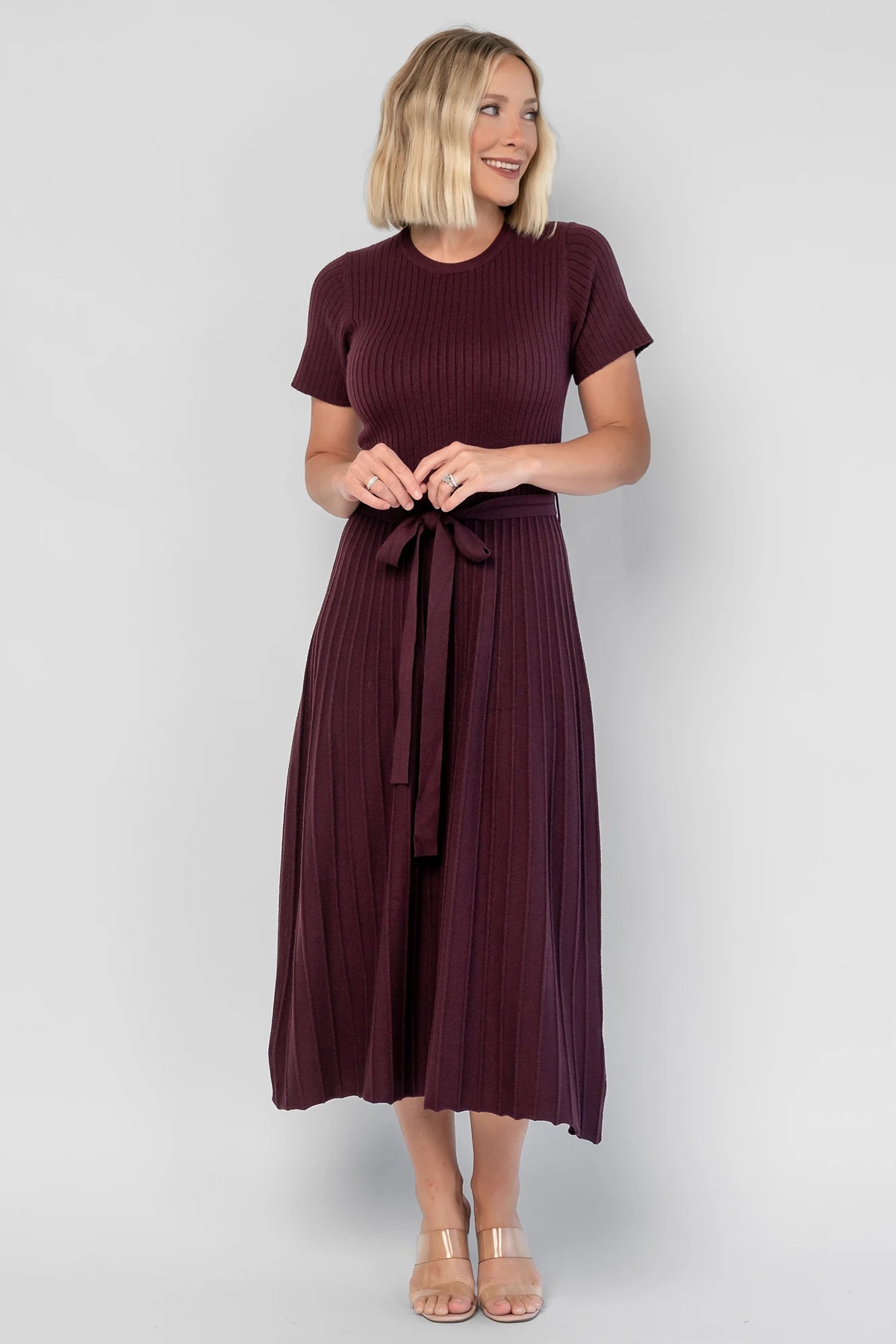 Jessamine Midi Dress in Dark Plum with a ribbed sweater knit, crew neckline, waist belt, and pleated midi skirt.