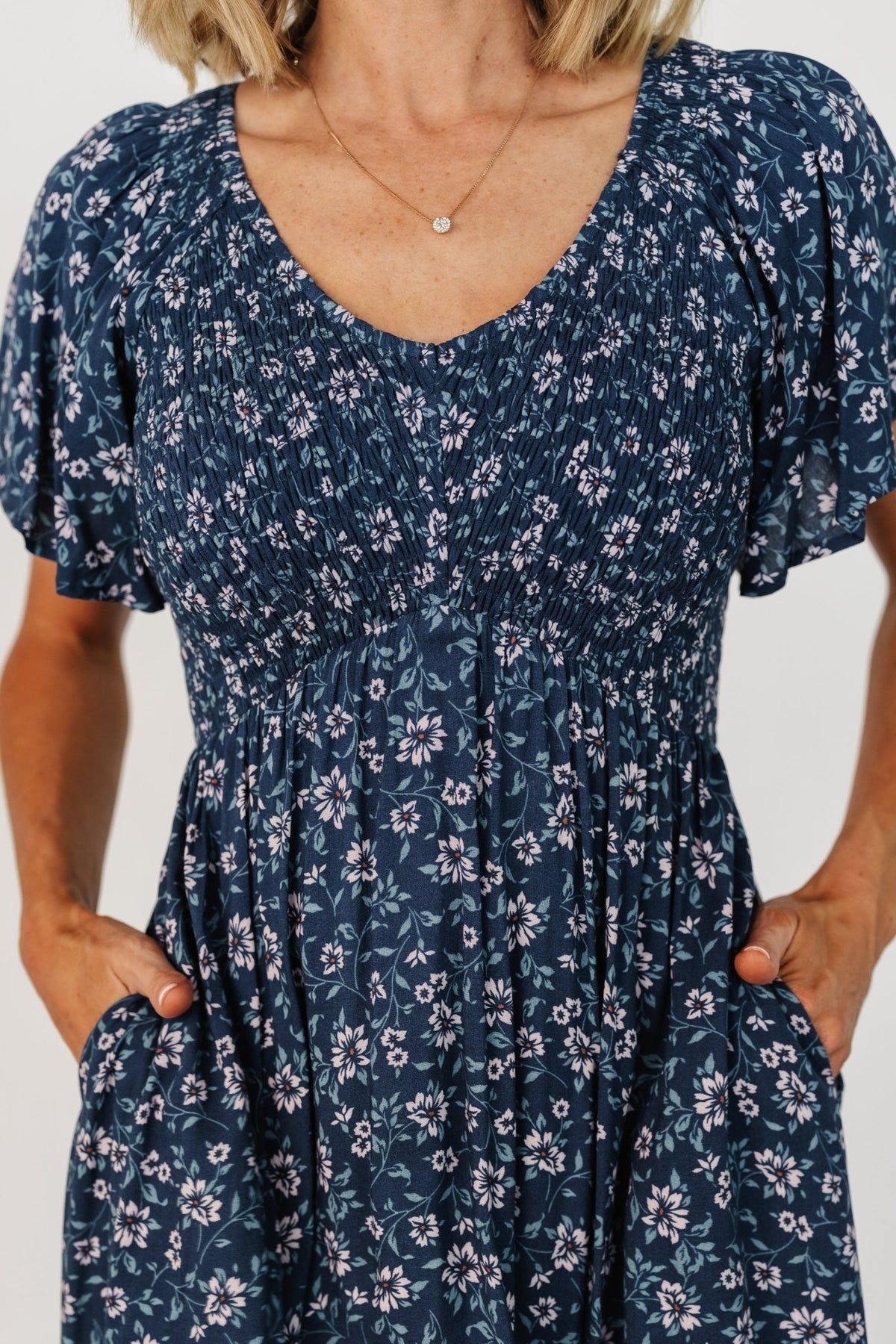 Close-up of smocked bust and center seam detail on the Joanie dress, showing texture and stitch work in blue floral.