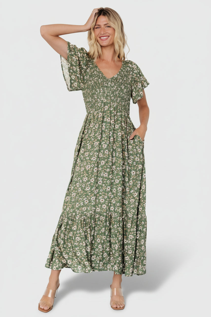 Three-quarter shot highlighting the dusty green floral print and flowy single-tier skirt, showing pocket placement and relaxed midi length.