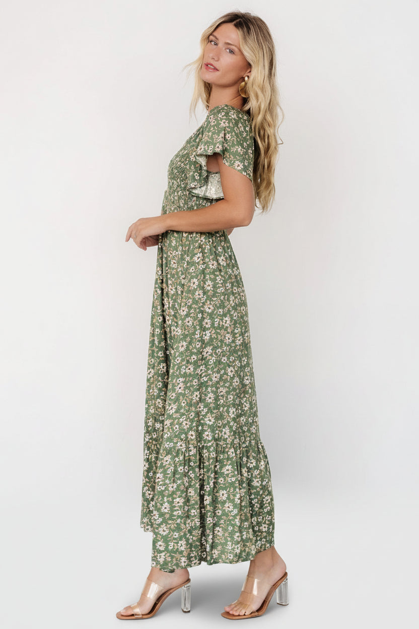 Styled image of the Joanie smocked midi dress on a model walking, illustrating the dress’s flow, tiered hem, and occasion-ready versatility.