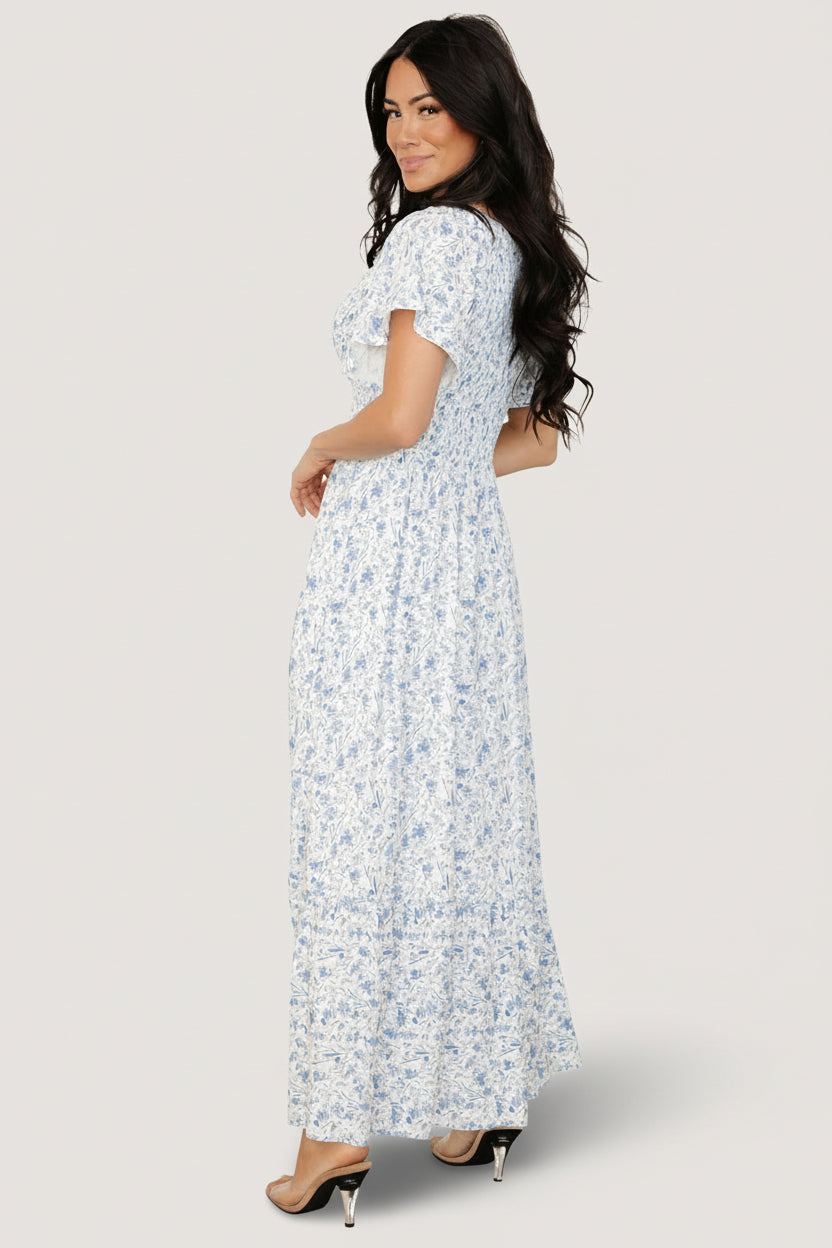 Close-up of smocked bust and center seam on white and blue floral dress, showing delicate rayon texture and shoulder smocking detail.