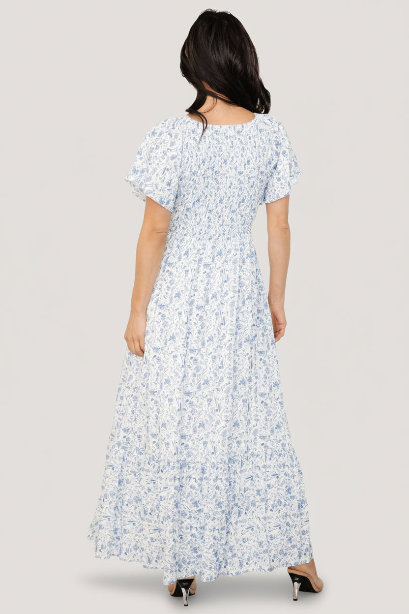 Detail view of flutter sleeve and side seam where the hidden pocket is located on the Joanie smocked midi dress in blue floral.