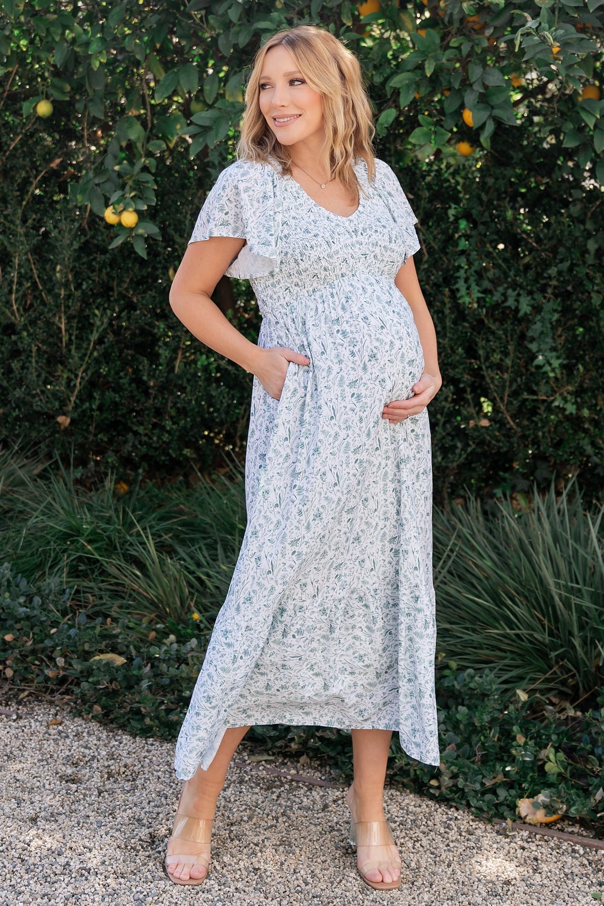 Front view of Joanie smocked midi dress in off-white with sage floral print, showing smocked bust, wide V-neck, and flutter sleeves.