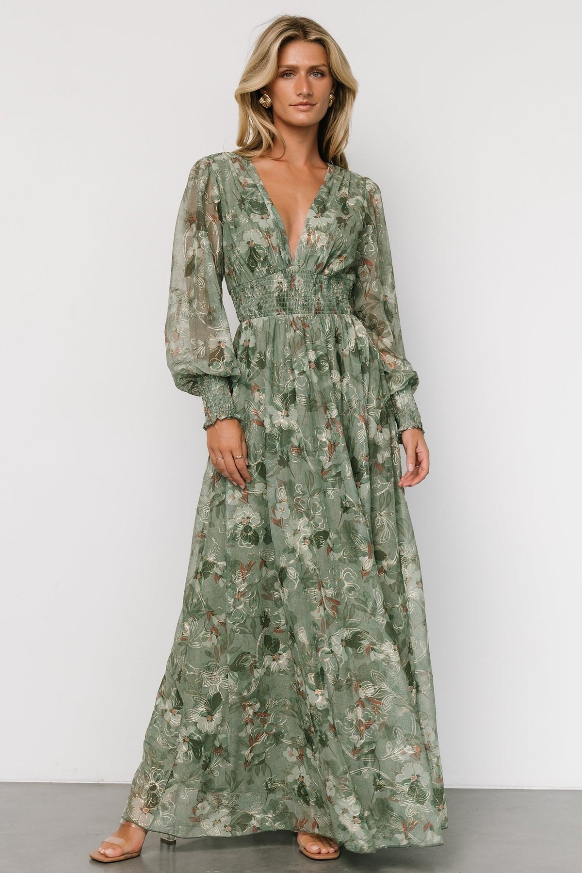 Model wearing sage tulle maxi dress showing gold floral embroidery, smocked cuffs, deep V-neck and flowing skirt for events.